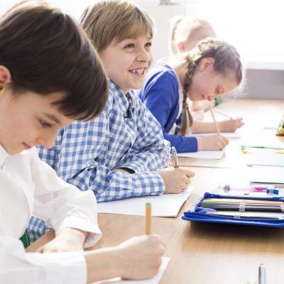 Happy hard-working kids writing an exam in primary school